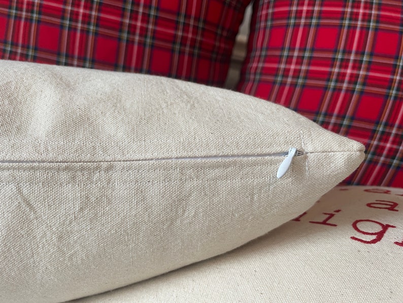 May include: A close-up of a beige pillow with a white zipper. The pillow is made of a soft, textured fabric.
