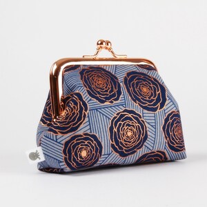 Peut inclure: Une petite bourse à monnaie bleue et dorée avec un motif floral et un fermoir en or rose.