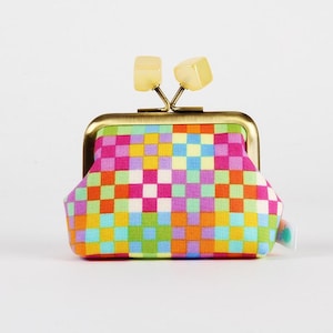 Peut inclure: Un petit porte-monnaie coloré avec un motif tissé aux couleurs rose, orange, jaune, vert et bleu. Il est doté d'un cadre couleur laiton et d'un fermoir avec deux accents carrés jaune clair.