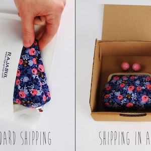 May include: A small floral patterned purse with a pink clasp and two pink buttons. The purse is shown in two different packaging options: a white padded envelope and a brown cardboard box. The text "STANDARD SHIPPING" is below the envelope and "SHIPPING IN A BOX" is below the box.