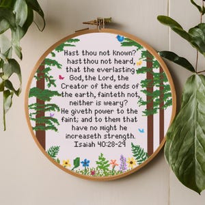 May include: A white embroidery hoop with a green forest scene and a bible verse from Isaiah 40:28-29. The verse reads: "Hast thou not known? hast thou not heard, that the everlasting God, the Lord, the Creator of the ends of the earth, fainteth not, neither is weary? He giveth power to the faint; and to them that have no might he increaseth strength. Isaiah 40:28-29"