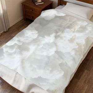 May include: A white duvet cover with a cloud-like pattern, covering a bed with a white pillow. The bedding has a soft, textured appearance. A wooden nightstand is visible in the background.