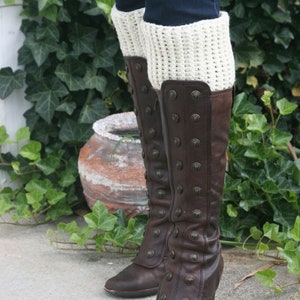 May include: Brown leather boots with a button closure and a cream crocheted leg warmer.