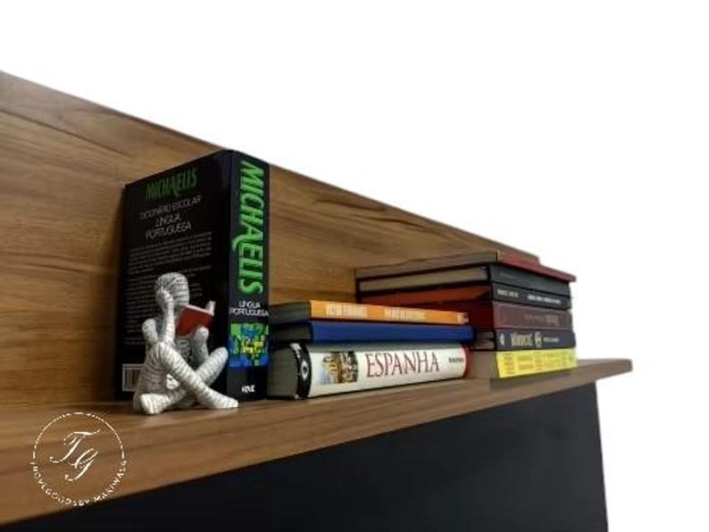 K&ouml;nnte beinhalten: Ein Holzregal mit einer Vielzahl von B&uuml;chern, die darauf gestapelt sind. Die B&uuml;cher sind in verschiedenen Farben und Gr&ouml;&szlig;en, und einige haben sichtbare Titel. Eine kleine silberne Figur eines lesenden Menschen steht auf dem Regal.