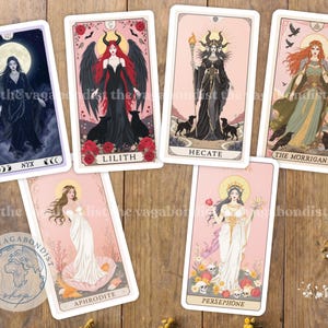 Puede incluir: Un conjunto de cartas de tarot con ilustraciones de figuras mitológicas. Las cartas muestran a Nyx, Lilith, Hécate, The Morrigan, Afrodita y Perséfone. Cada carta tiene un diseño único con ilustraciones detalladas y etiquetas de texto.