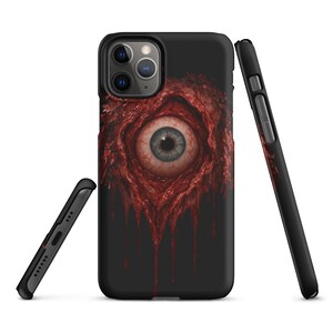 May include: Black phone case featuring a detailed, realistic eye design. The eye has a blue iris and is surrounded by a red, fleshy texture with dripping blood-like elements. The case is shown from multiple angles.