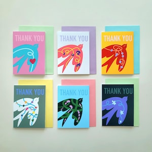May include: Six "Thank You" greeting cards with bird designs in various colours. Each card has a different colour scheme, including pink, purple, yellow, green, and blue, with matching envelopes. The cards are neatly arranged on a light background.