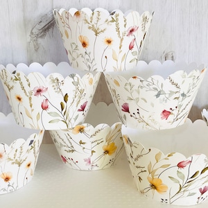 May include: Set of six white cupcake liners with a floral pattern featuring watercolor-style pink, yellow, and green flowers and leaves.