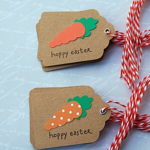 May include: Two brown gift tags with red and white twine. Each tag features a paper carrot with a green top and the text "hoppy easter".