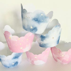 May include: A stack of cupcake liners with a blue and pink watercolor galaxy design and gold glitter stars.