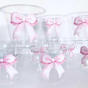 May include: Set of clear plastic cups with pink watercolor bow designs. The cups are perfect for parties, showers, or other special occasions.