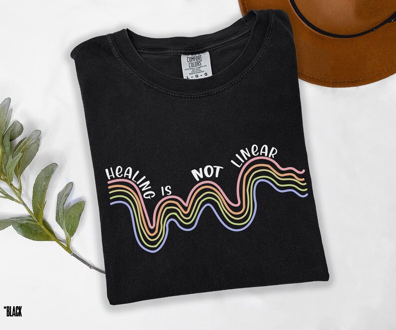 May include: Black t-shirt with a rainbow graphic and the text "Healing is not linear".