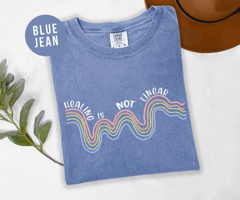 May include: A blue jean t-shirt with a rainbow graphic and the text "Healing is not linear".
