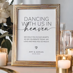 Puede incluir: Un letrero enmarcado con el texto "DANCING WITH US IN heaven". El letrero está en un marco dorado e incluye los nombres Amy & Adrian y la fecha 04.09.20XX. El letrero está rodeado de velas y flores.