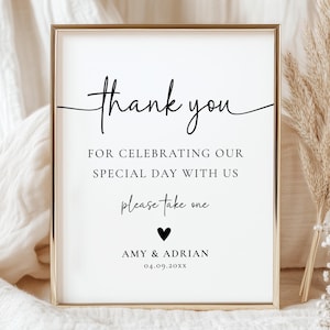 May include: A framed sign with gold trim and the words "thank you" in elegant script. The sign includes the text "FOR CELEBRATING OUR SPECIAL DAY WITH US" and "please take one." A heart and names are at the bottom. The date is 04.09.20XX.