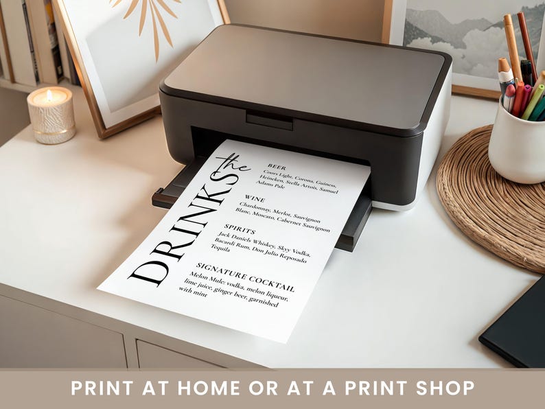 May include: A black and white printer printing a drinks menu. The menu lists beer, wine, spirits, and a signature cocktail. The text "DRINKS" is prominently displayed. The image also includes the text "PRINT AT HOME OR AT A PRINT SHOP."