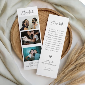 May include: Two white invitation cards with photos and text. One card has three photos of smiling people. The other card has a message and a heart symbol. The text says "Will you be my bridesmaid?" and "Elizabeth."