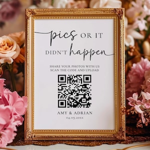 Könnte beinhalten: Ein goldgerahmtes Schild mit dem Text "pics OR IT DIDN'T happen" in schwarzer Schrift. Es enthält einen QR-Code und den Text "SHARE YOUR PHOTOS WITH US SCAN THE CODE AND UPLOAD". Der Hintergrund zeigt rosa und pfirsichfarbene Blumen.