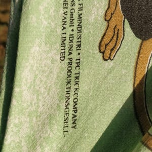 May include: A green t-shirt with a faded white print of a cartoon monkey. The text on the shirt reads "&copy;1997 AB SVENSK FILMINDUSTRI * TFC TRICKCOMPANY FILMPRODUKTIONS GmbH * IDUNA PRODUKTIONSGESELL-SCHAFT GmbH * NEI.VANA LIMITED."