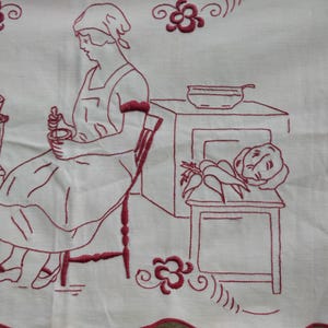 May include: Red embroidered design on white fabric depicting a woman sitting in a chair holding a bowl, a stove with a pot on top, and a table with vegetables on it.