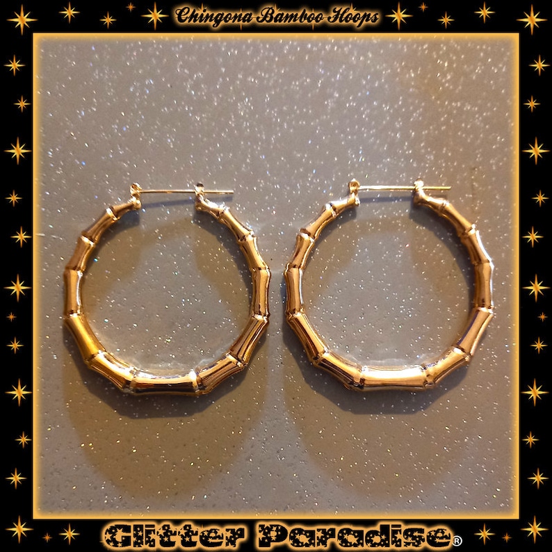 K&ouml;nnte beinhalten: Ein Paar goldfarbene Creolen mit einem strukturierten Bambus-Design. Der Text Chingona Bamboo Hoops ist oben sichtbar, und der Text Glitter Paradise ist unten im Bildrahmen zu sehen.