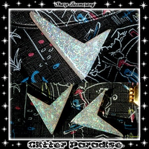 May include: Two silver glitter boomerang shapes on a black background with the text "Sharp Boomerang" and "Glitter Paradise" printed on the fabric.