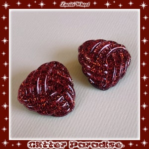 May include: Two red glitter heart-shaped buttons with a knotted design.