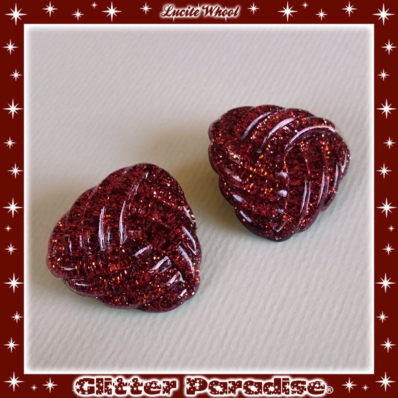 May include: Two red glitter heart-shaped buttons with a knotted design.