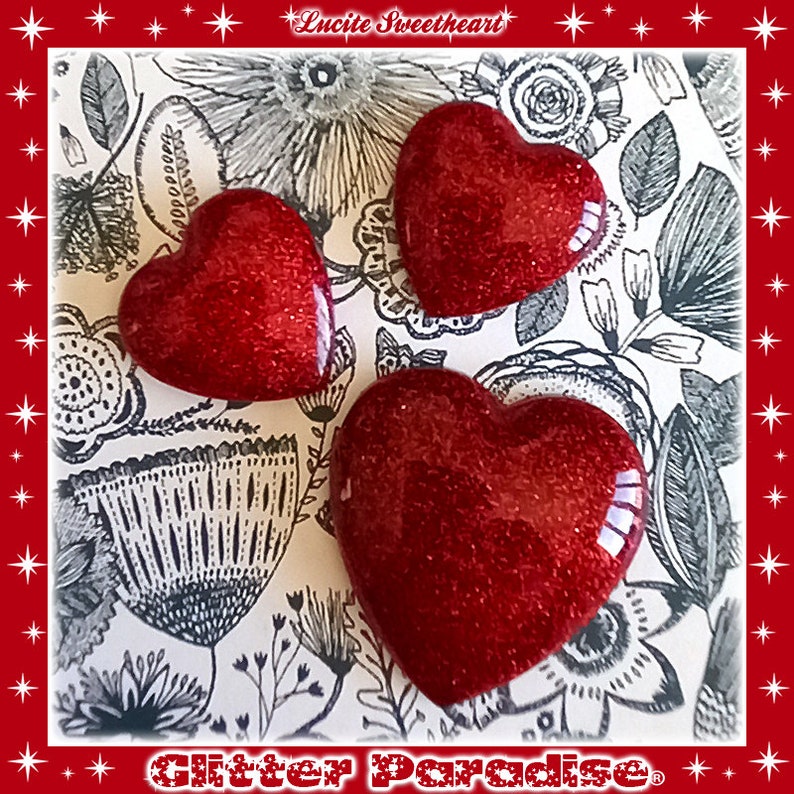 May include: Three red glitter heart-shaped ornaments on a black and white floral background. The text "Lucite Sweetheart" and "Glitter Paradise" are visible in the image.