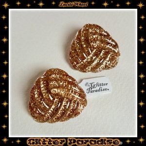 May include: A pair of gold glitter earrings in a woven design. The earrings are labeled "Glitter Paradise."
