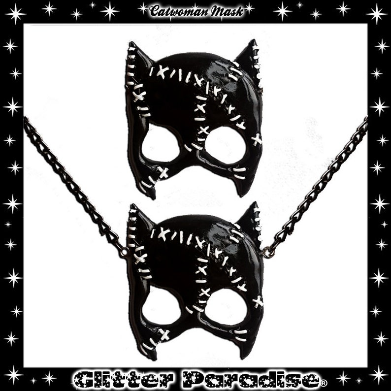 May include: Black catwoman mask necklace with a chain. The mask has white stitching details and is made of a shiny black material.