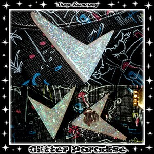 May include: Two silver glitter boomerang earrings with a sharp point. The earrings are on a black fabric background with a white and blue pattern.