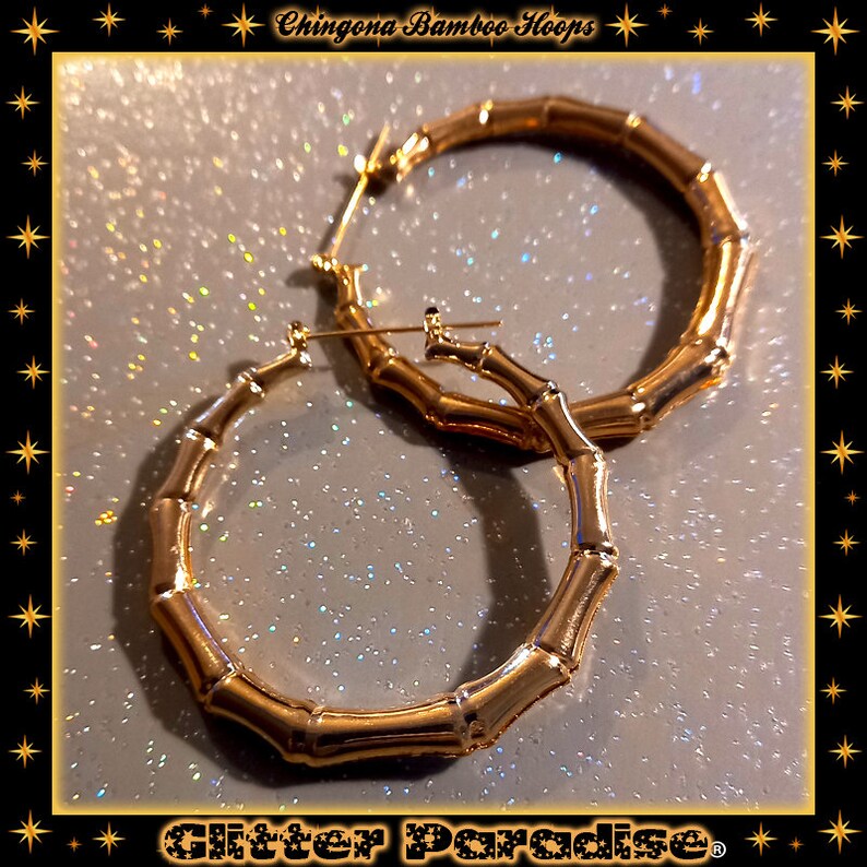 K&ouml;nnte beinhalten: Ein Paar goldfarbene Creolen mit einem strukturierten Bambus-Design. Die Ohrringe haben eine kreisf&ouml;rmige Form mit einem segmentierten Aussehen, das an Bambusstangen erinnert. Der Text "Chingona Bamboo Hoops" und "Glitter Paradise" ist zu sehen.