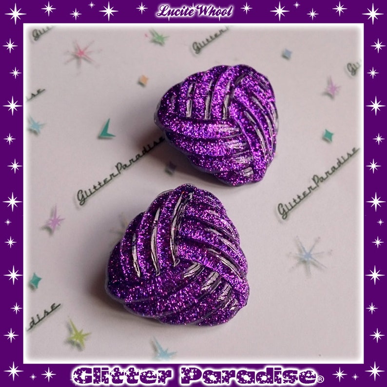 May include: Two purple heart-shaped earrings with a glitter finish and a woven design. The earrings are on a white background with a glitter paradise logo.