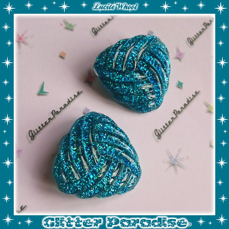 May include: A pair of turquoise blue clip-on earrings with a woven design and glitter finish. The earrings are heart-shaped and have a retro style.