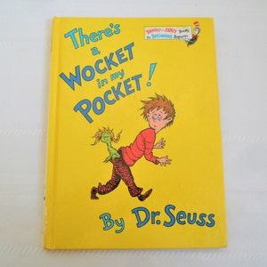 May include: A yellow book cover with the title "There's a WOCKET in my POCKET!" by Dr. Seuss. The cover features an illustration of a boy running away from a green creature with a long tail.