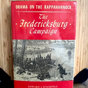 May include: A red hardcover book titled "The Fredericksburg Campaign: Drama on the Rappahannock" by Edward J. Stackpole. The cover features a black and white illustration of soldiers crossing a river in winter.