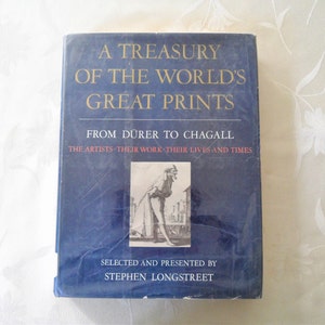 May include: A blue hardcover book titled "A Treasury of the World's Great Prints: From Dürer to Chagall." The book features a black and white illustration of a man in a long coat and hat on the front cover. The text "The Artists - Their Work - Their Lives and Times" is printed below the title. The book is by Stephen Longstreet.