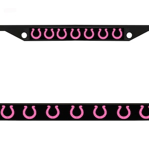 May include: Black license plate frame with pink horseshoe logos. The frame has a black background with a row of pink horseshoes along the top and bottom.