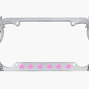 May include: Silver-colored license plate frame with palm tree accents on each side. The bottom of the frame features six pink sea turtle silhouettes. The frame is designed to hold a standard license plate.
