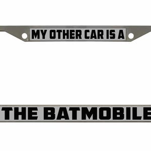 Puede incluir: Un marco de matrícula de metal plateado con el texto "My other car is a The Batmobile" impreso en negro sobre un fondo blanco.