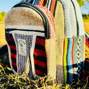May include: A small, multi-coloured hemp backpack with a zipper closure and a "Himalaya Hemp Textile" label. The backpack is made of woven fabric with a variety of colours and patterns, including red, blue, green, yellow, and white.