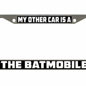 Puede incluir: Un marco de matrícula de coche plateado con texto en blanco y negro que dice "My other car is a The Batmobile".