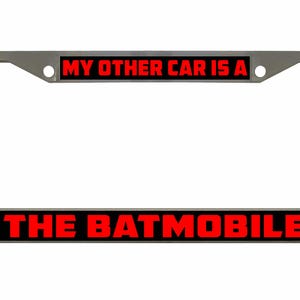 Puede incluir: Un marco de matrícula de coche plateado con fondo negro y texto rojo que dice "My other car is a The Batmobile".