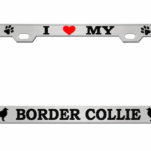 May include: A silver license plate frame with the text "I ❤️ MY BORDER COLLIE" in black. The heart is red. The frame has paw prints and dog bone designs. Silhouettes of Border Collies are on each side.