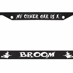 Puede incluir: Marco de matrícula negro con el texto "MY OTHER CAR IS A BROOM" en blanco. El marco tiene un patrón de fibra de carbono y presenta una silueta de una bruja en una escoba.