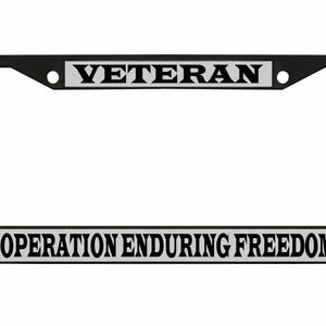 May include: Black license plate frame with the word "VETERAN" at the top and "OPERATION ENDURING FREEDOM" at the bottom in bold, black letters. The text is on a silver background.
