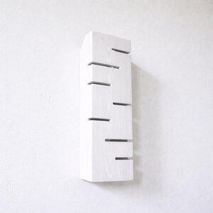 A vertical rectangular wooden wall sconce with warm LED light shining through carved horizontal openings. The wood has a natural grain and rustic brown finish. The style is minimalist, cozy, and modern, suitable for hallway, living room, or bedroom wall lighting.