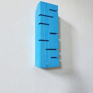 A vertical rectangular wooden wall sconce with warm LED light shining through carved horizontal openings. The wood has a natural grain and rustic brown finish. The style is minimalist, cozy, and modern, suitable for hallway, living room, or bedroom wall lighting.