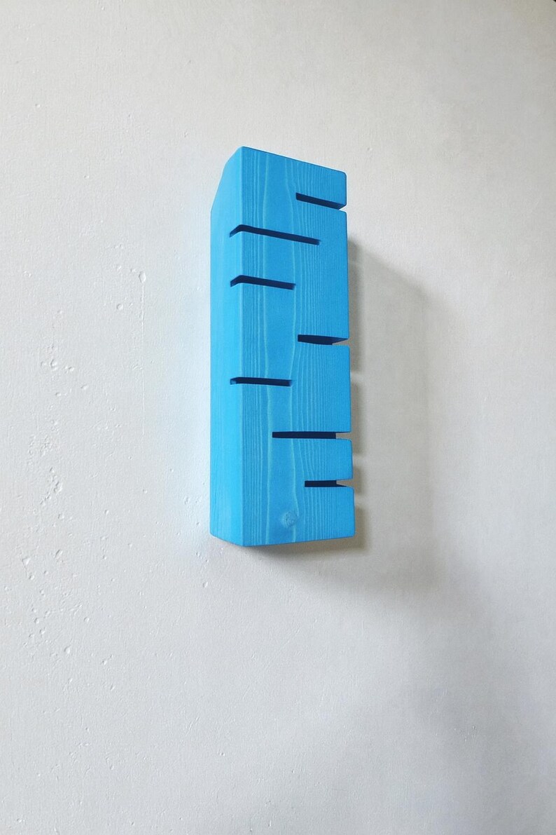 A vertical rectangular wooden wall sconce with warm LED light shining through carved horizontal openings. The wood has a natural grain and rustic brown finish. The style is minimalist, cozy, and modern, suitable for hallway, living room, or bedroom wall lighting.